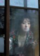 A woman looking out of a window with a broken glass.