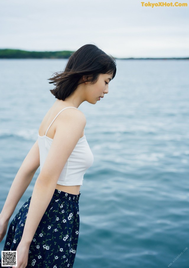 A woman standing on the edge of a body of water.