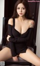 A woman in a black dress sitting on a chair.