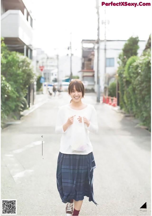 A woman walking down a street holding a bag.