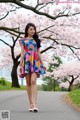 A woman in a colorful dress standing in front of a tree.