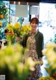 A woman standing in front of a bunch of flowers.