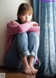 A young woman sitting on the floor with her legs crossed.