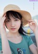 A young woman wearing a straw hat and a green shirt.