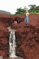 A woman standing on top of a cliff next to a waterfall.