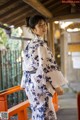 A woman in a blue and white kimono standing on a bridge.