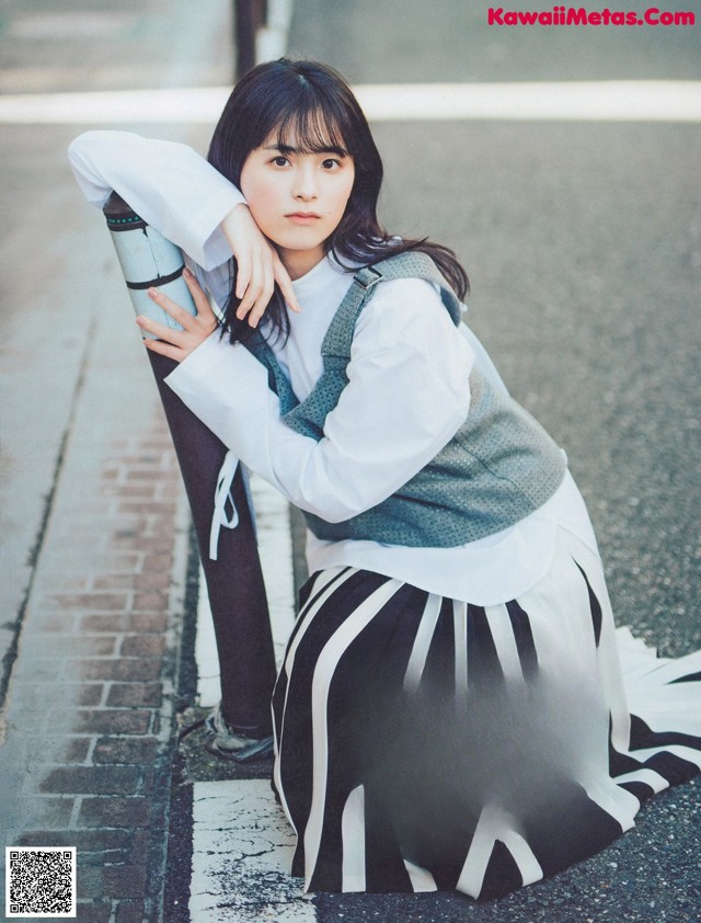 A woman leaning against a pole on the side of the road.