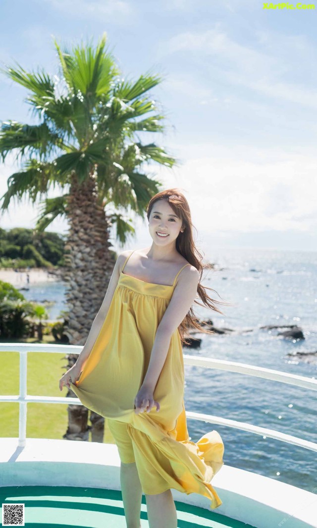 A woman in a yellow dress standing on a boat.