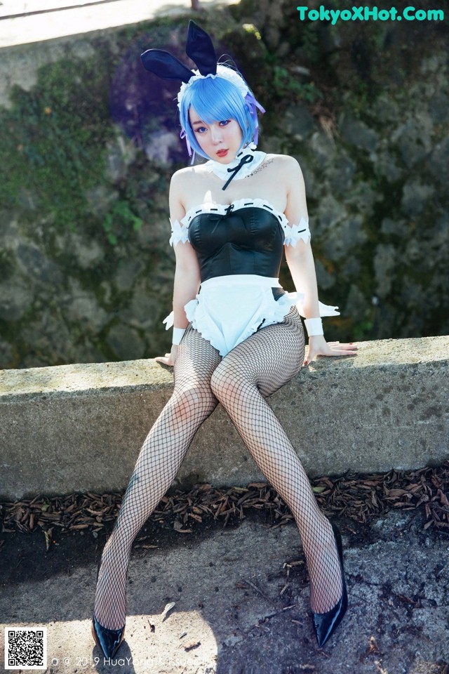 A woman in a bunny costume sitting on a stone wall.