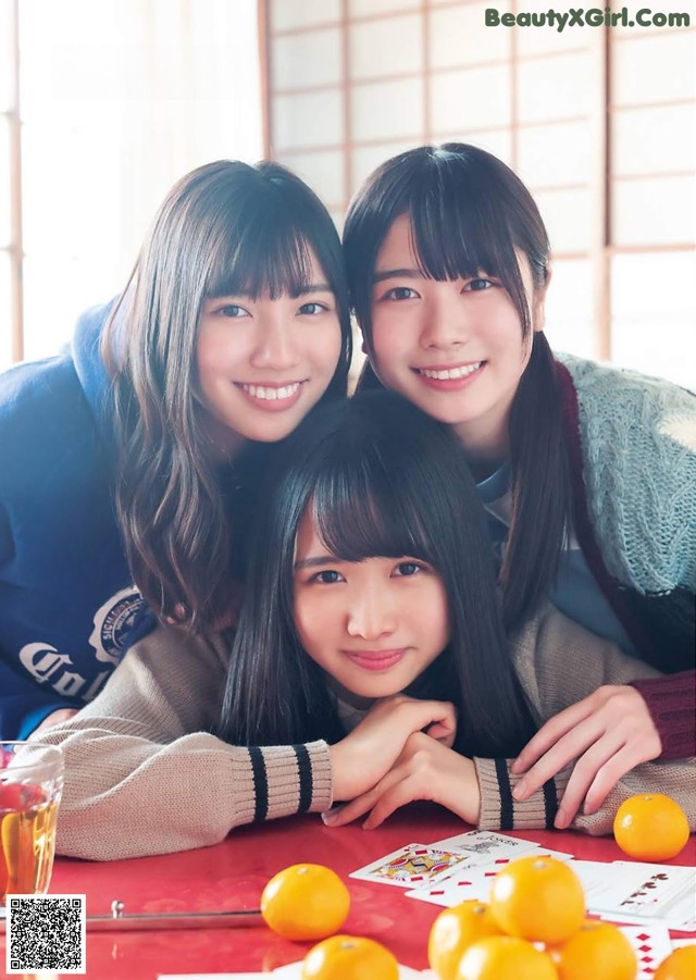 A group of young women sitting at a table with oranges.